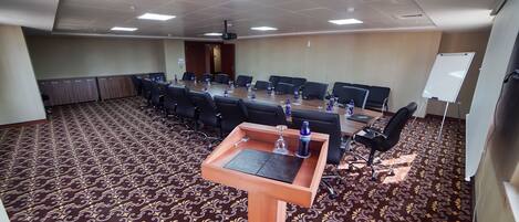 A conference room with a long table, multiple chairs, water bottles, and a whiteboard.