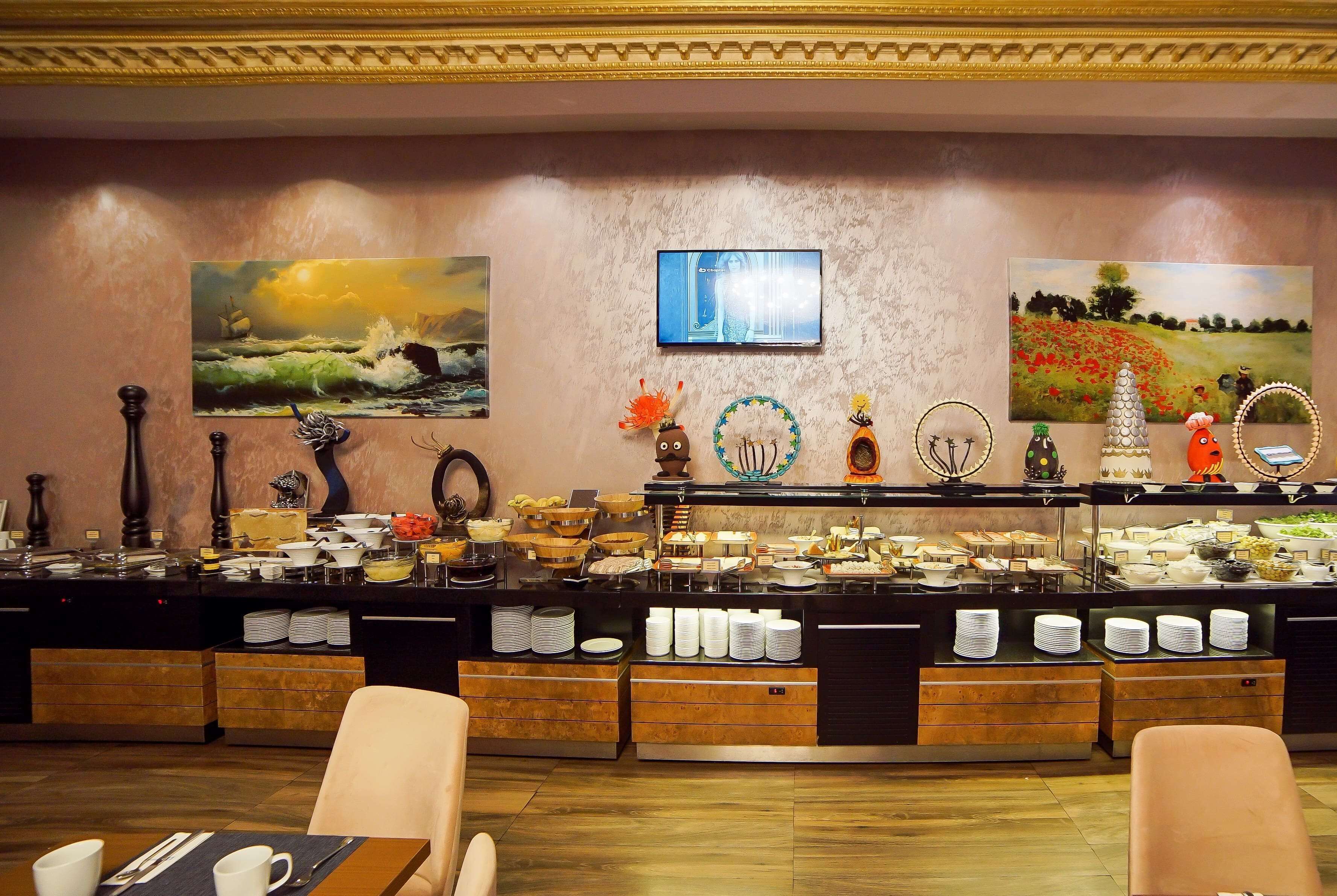A buffet setup with various food items and a television screen.