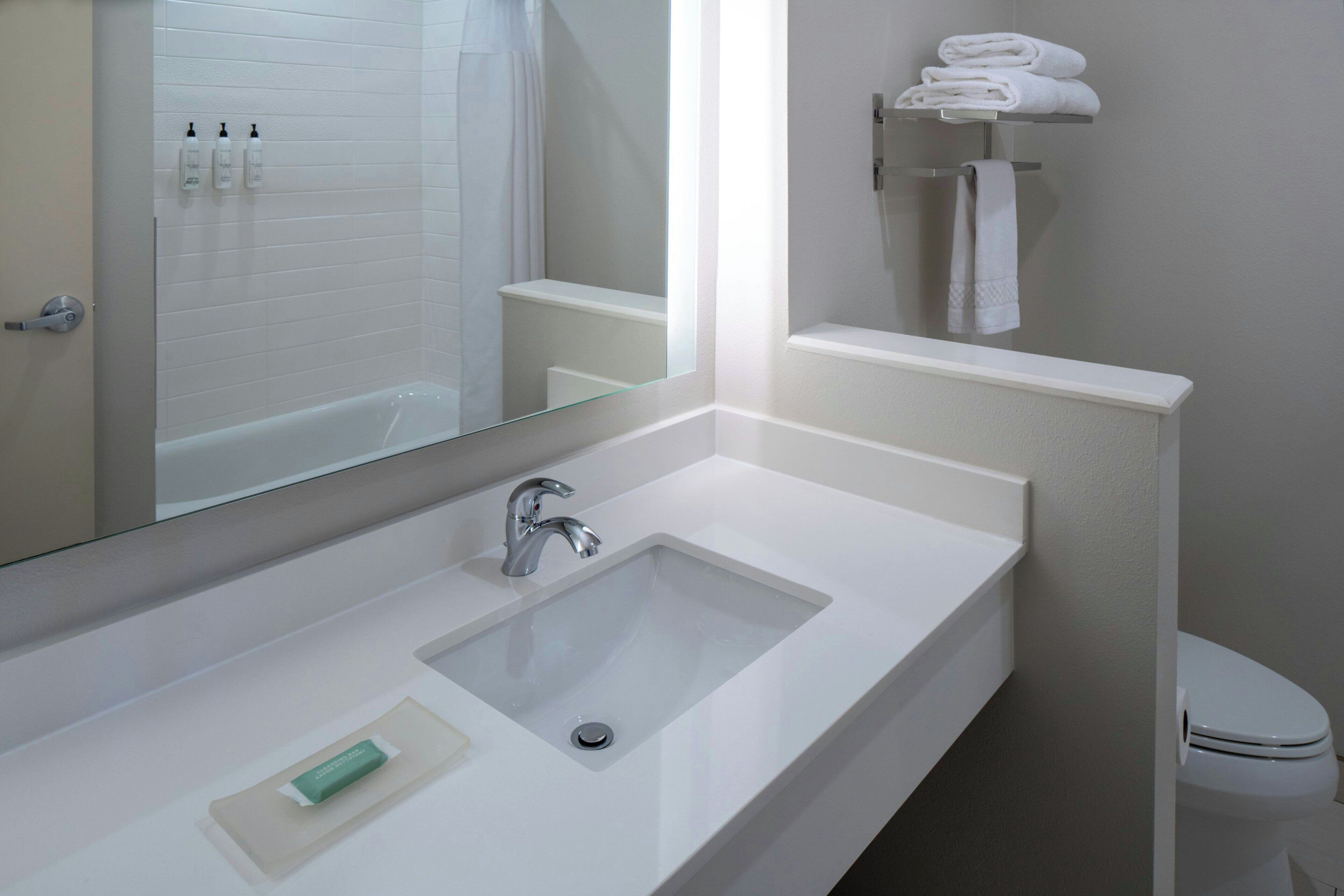 A bathroom with a white sink, a mirror, a toilet, and a towel rack.