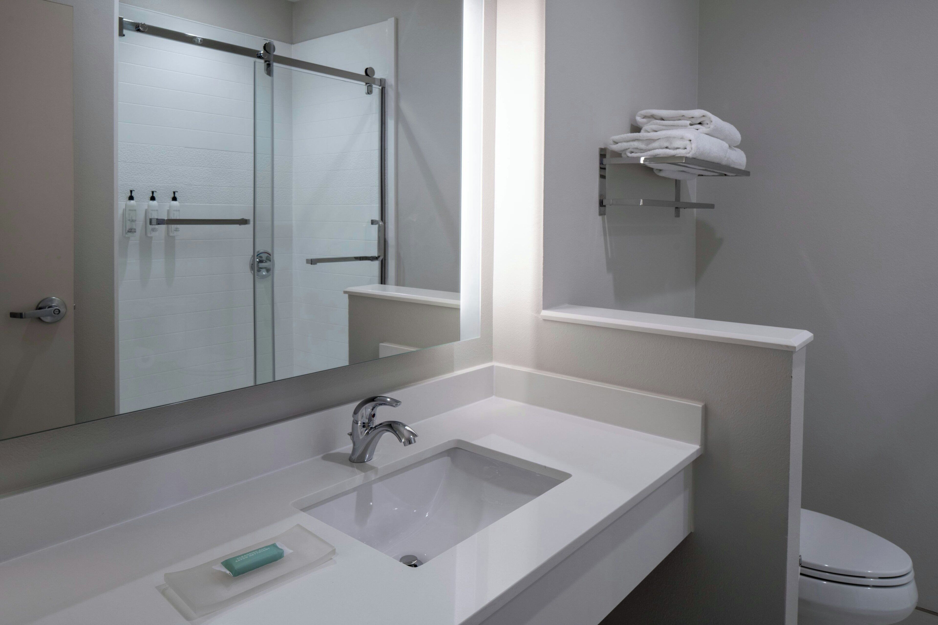 A bathroom with a white sink, a mirror, a towel rack, and a toilet.