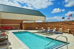 Une piscine avec des chaises longues et un mur en briques.