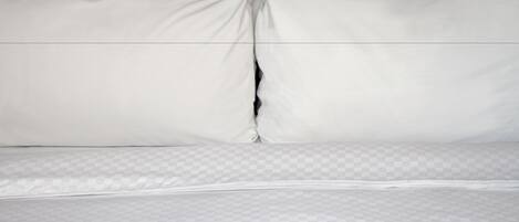 Una cama bien hecha con ropa de cama blanca y un cubrecolchón a cuadros.