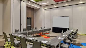 A conference room with a long table, chairs, a projector screen, and a door.
