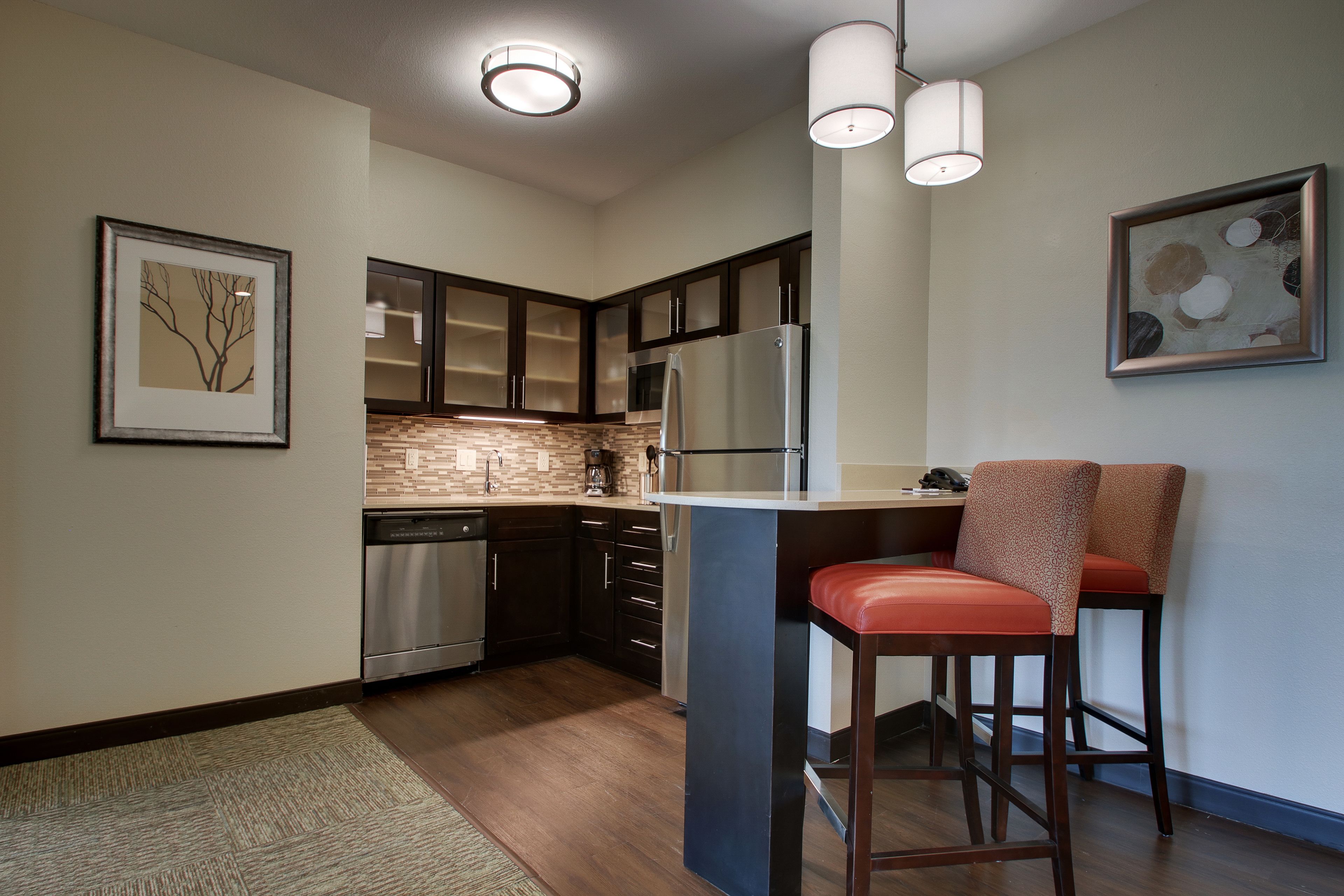 A modern kitchen with dark wooden cabinets, stainless steel appliances, and a central island with bar stools.