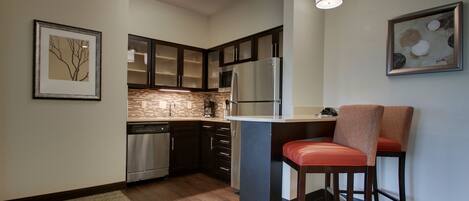 A modern kitchen with dark wooden cabinets, stainless steel appliances, and a central island with bar stools.