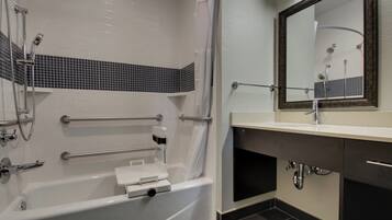 Un baño con bañera, ducha, lavamanos con espejo y toallero.