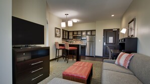 A compact living space with a kitchenette, a dining area, a sofa, and a TV. - Staybridge Suites Plano - The Colony by IHG (The Colony)