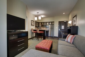 A compact living space with a kitchenette, a dining area, a sofa, and a TV. - Staybridge Suites Plano - The Colony by IHG (The Colony)