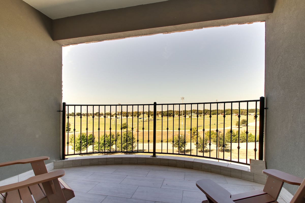 A balcony with a curved floor, a metal railing, and two wooden benches.