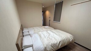 Un dormitorio con cama, ventana con persianas y puerta que da a otra habitación.