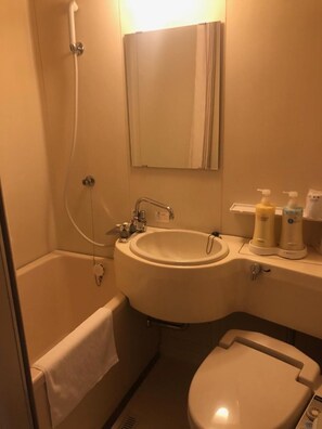 Ein Badezimmer mit Badewanne, Waschbecken und Toilette. Auf dem Waschbecken stehen zwei Seifenspender.