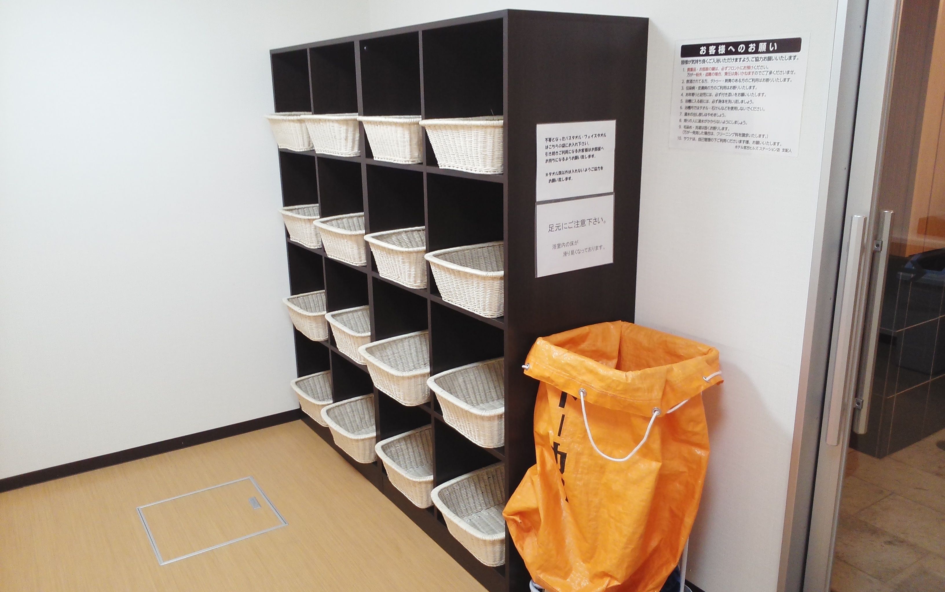 A storage unit with multiple wicker baskets and a yellow bag hanging on the wall.