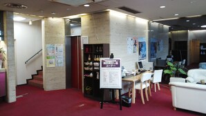 A lobby with a reception desk, a staircase, and a seating area with chairs and a sofa.