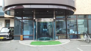 A modern building with a glass entrance and a green mat at the door.