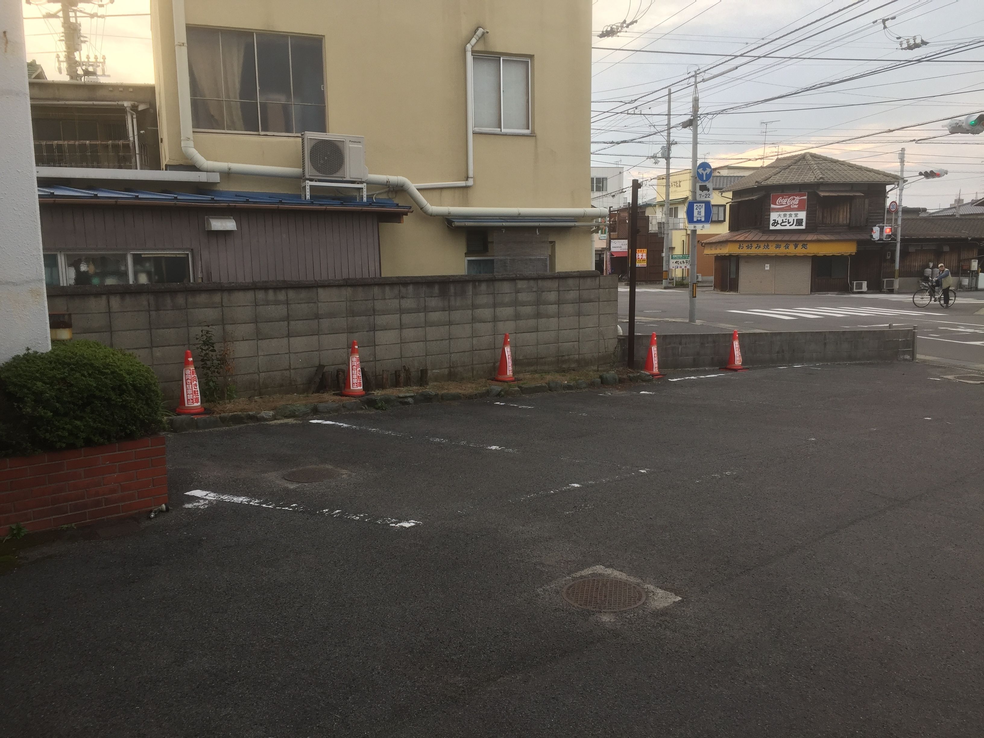 A street view with a building, traffic cones, and a Coca-Cola sign.