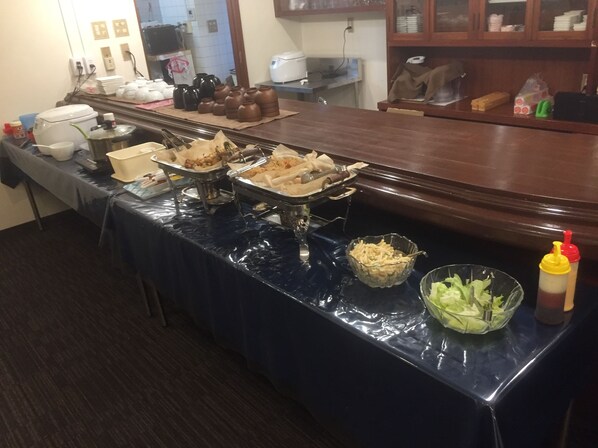 A buffet table with various food items and condiments.