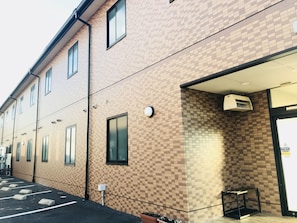 Un edificio con fachada de ladrillo a cuadros, múltiples ventanas y un estacionamiento.