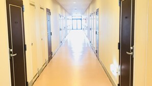A long, well-lit hallway with doors on both sides leading to individual rooms. - Hotel Tajimi Hills My Room (Tajimi)