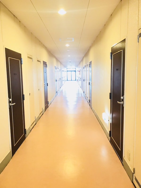 Un pasillo largo y bien iluminado con puertas a ambos lados que dan a habitaciones individuales.