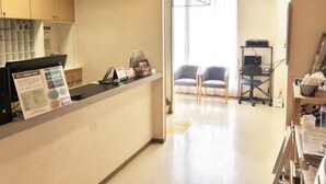 A reception area with a counter, chairs, a computer, and a window with curtains. - Hotel Tajimi Hills My Room (Tajimi)