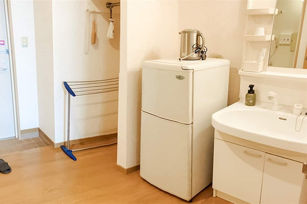 Ein kleines Badezimmer mit einem weißen Waschbecken, einem Spiegel und einem kleinen Kühlschrank.