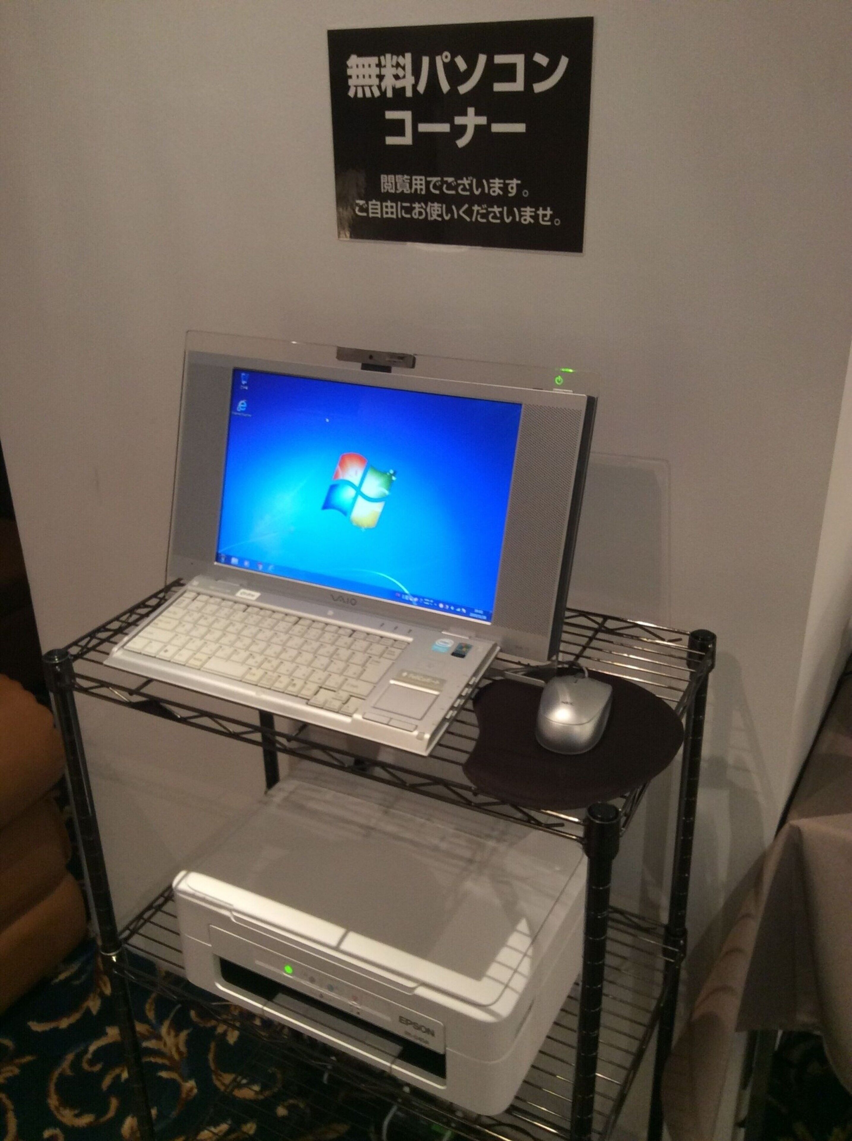 A laptop on a shelf with a printer below it, and a sign above the shelf.