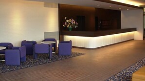 Un hall d’entrée avec un comptoir de réception, des sièges violets et une moquette à motifs.