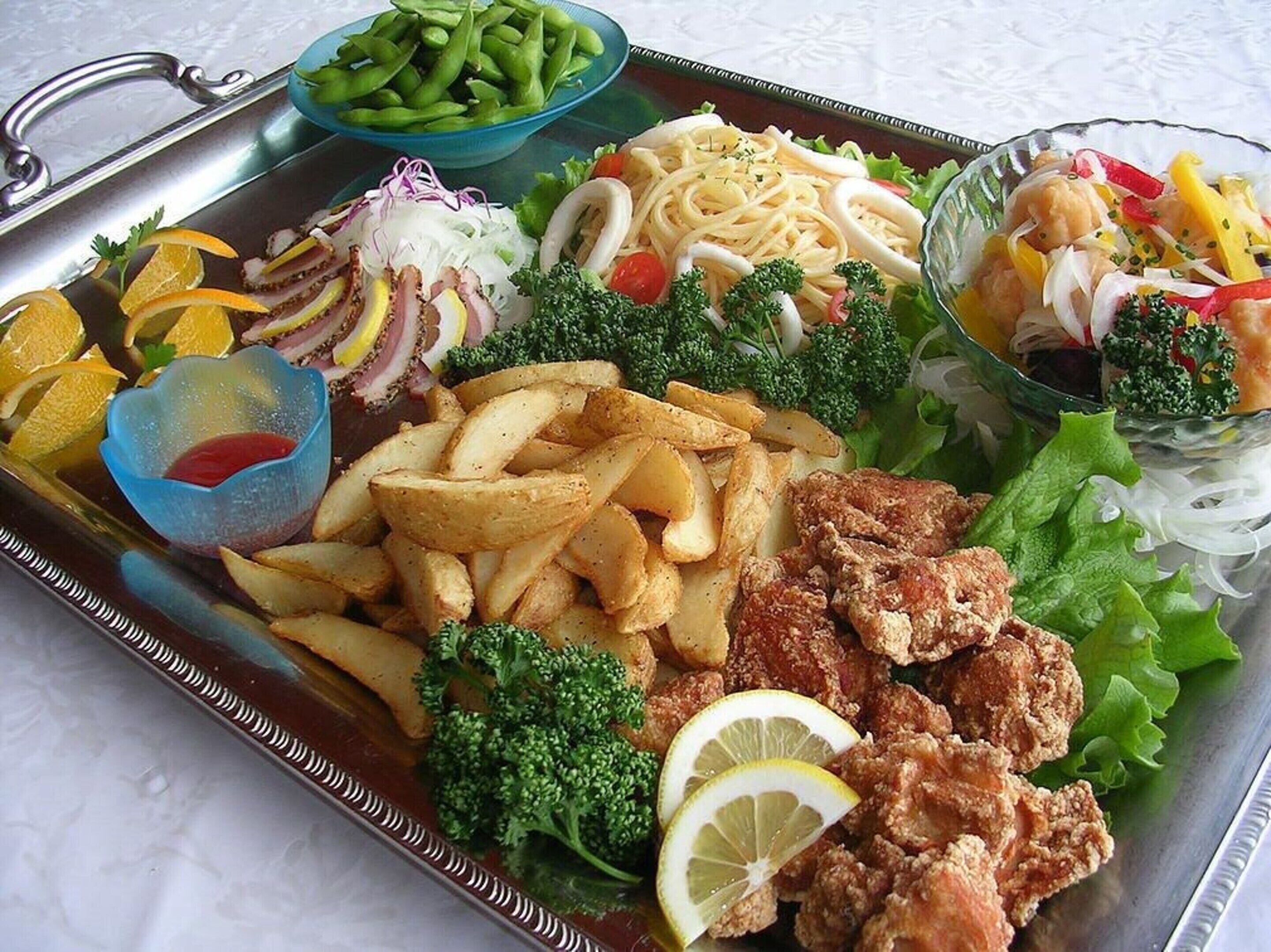 A tray with various foods including fries, breaded chicken, pasta, and vegetables.
