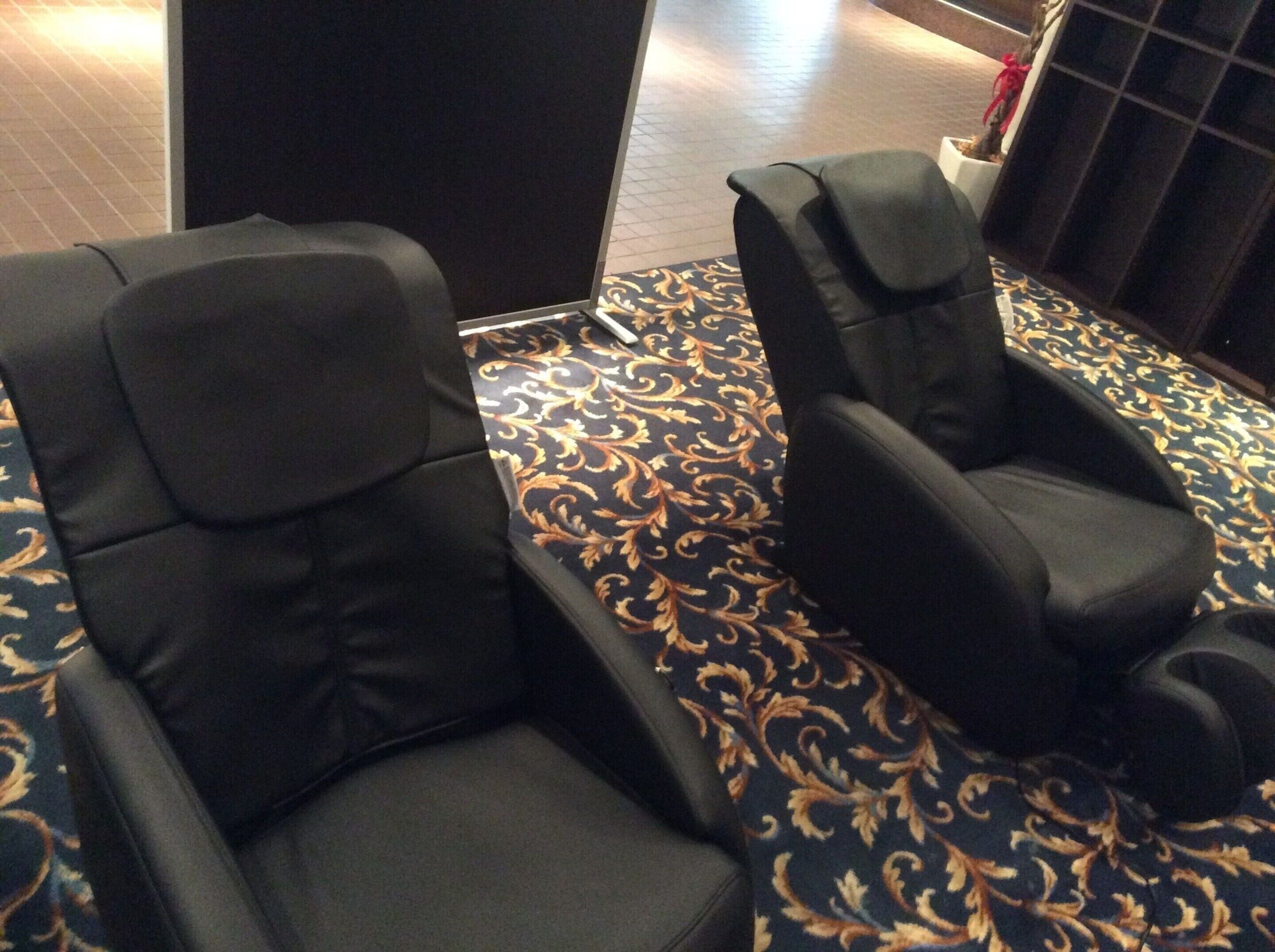 Dos sillones de cuero negro sobre una alfombra estampada.
