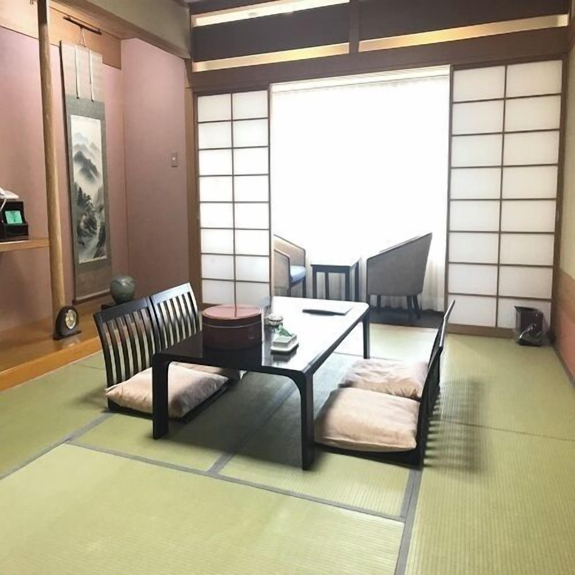 A tatami mat room with a low table, cushions, and a traditional Japanese sliding door.