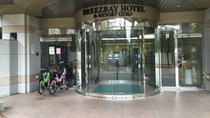 La entrada del BreezeBay Hotel & Resort Gero, con una puerta giratoria y un felpudo verde en la base.
