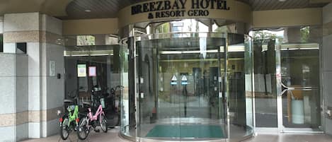 The entrance of BreezeBay Hotel & Resort Gero with a revolving door and a green mat at the base.