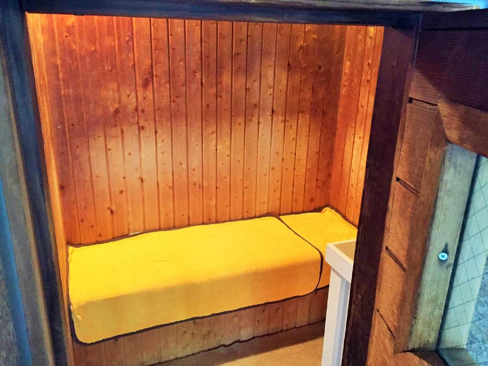 A wooden sauna with a bench and a bench cover.