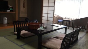 Una habitación tradicional japonesa con suelo de tatami, una mesa baja con cojines y una puerta corredera estilo shoji.