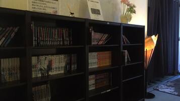 A bookshelf filled with books, a vase with flowers, and a lamp.