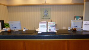 Un comptoir d’accueil d’hôtel équipé d’un écran d’ordinateur, d’un téléphone et de brochures d’information.