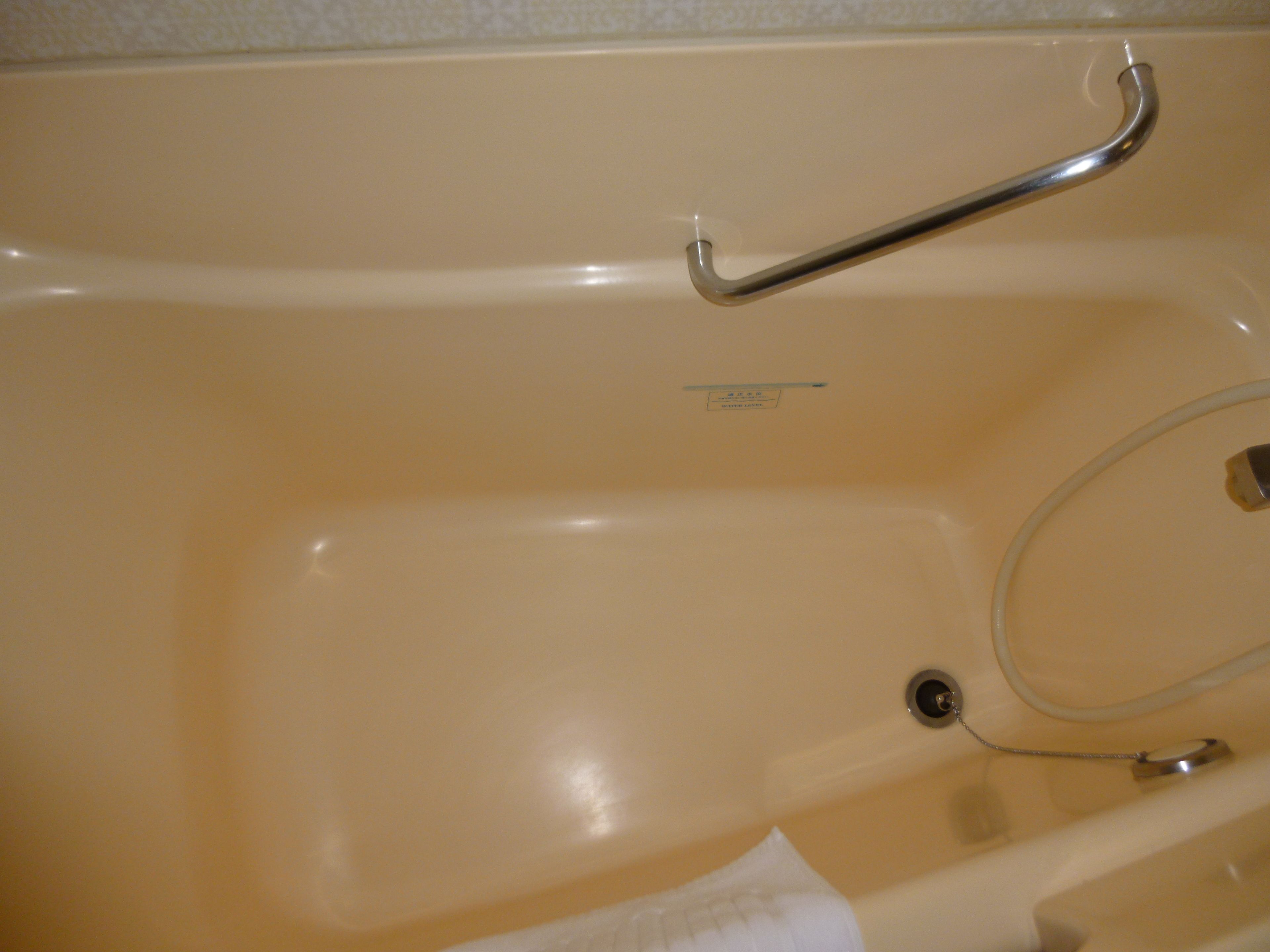 A bathtub with a grab bar, a drain, and a faucet.