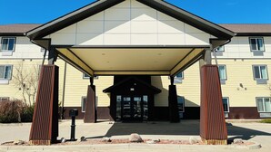 A multi-story building with a covered entrance, large windows, and a flat roof. - Black Gold Suites Tioga (Tioga)