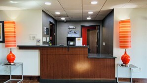 A reception desk with a wooden counter, two red lamps, a security camera, and a sign on the wall. - Black Gold Suites Tioga (Tioga)