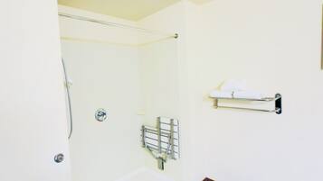 Un baño con ducha, toallero y retrete.