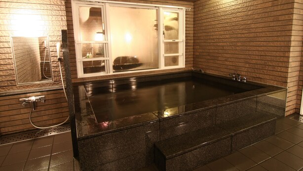 A spa area with a large soaking tub, a glass-enclosed shower, and a wooden wall. - Hotel Crown Hills Kimitsu (Kimitsu)