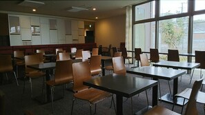 A dining area with tables and chairs, large windows, and a wall with framed pictures. - Hotel Crown Hills Kimitsu (Kimitsu)