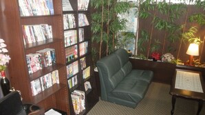 Um espaço aconchegante para leitura, com um sofá de couro, uma estante repleta de livros e uma mesinha com abajur.