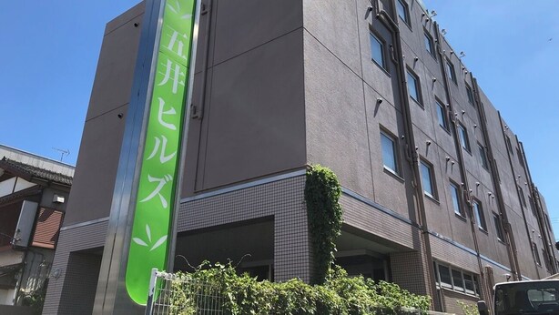 Um edifício com vários andares e uma placa verde na lateral.