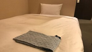 Cama bem arrumada com manta dobrada em quarto de hotel.