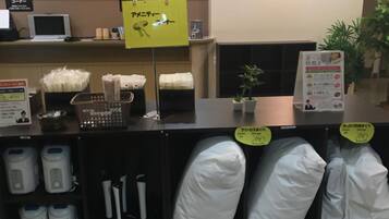 A hotel reception area with a counter, a signboard, and a display of pillows and toiletries.