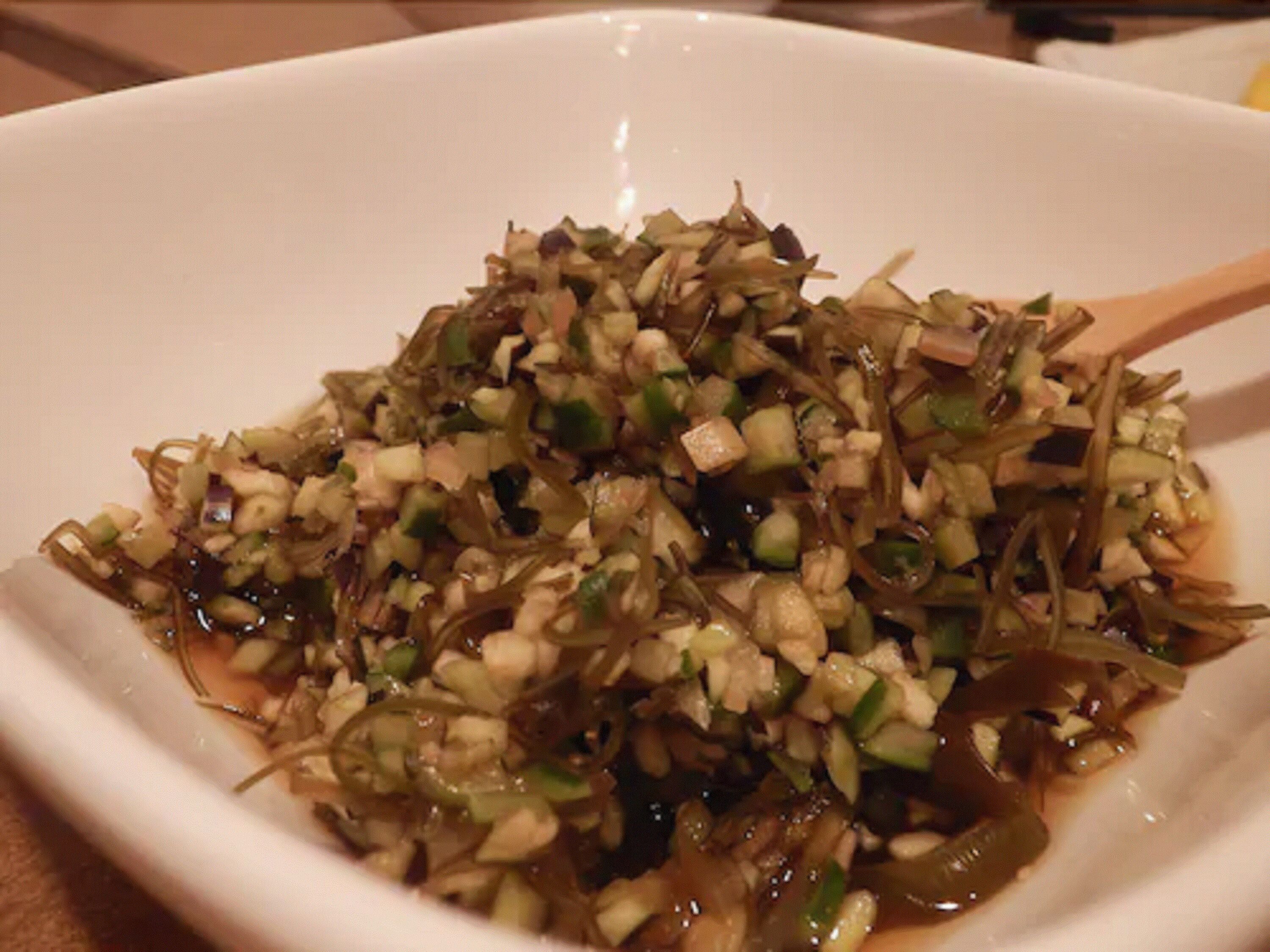 A white bowl filled with a chopped vegetable salad.