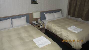 A hotel room with two beds, a nightstand with a lamp and phone, a picture on the wall, and a window with curtains.