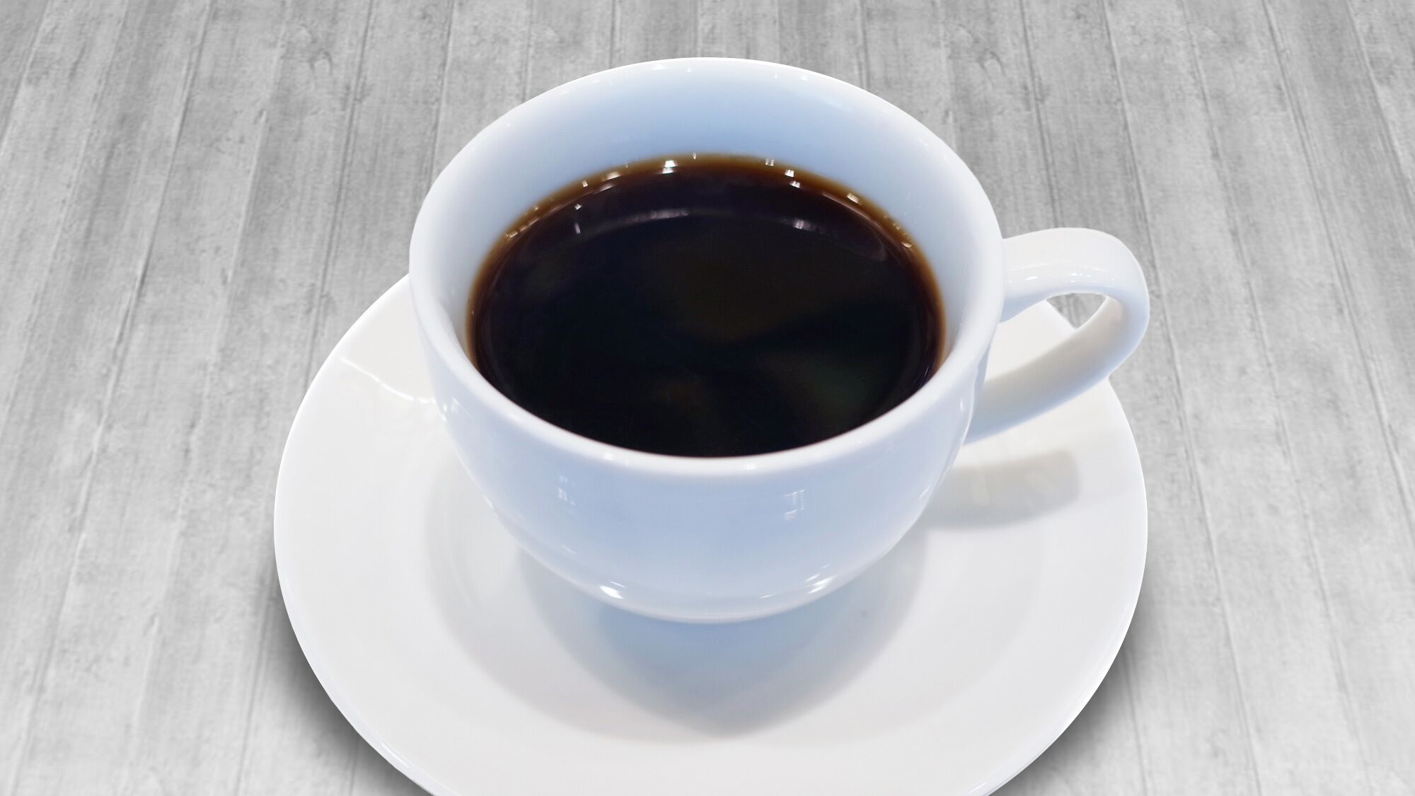 A white cup of coffee on a saucer.