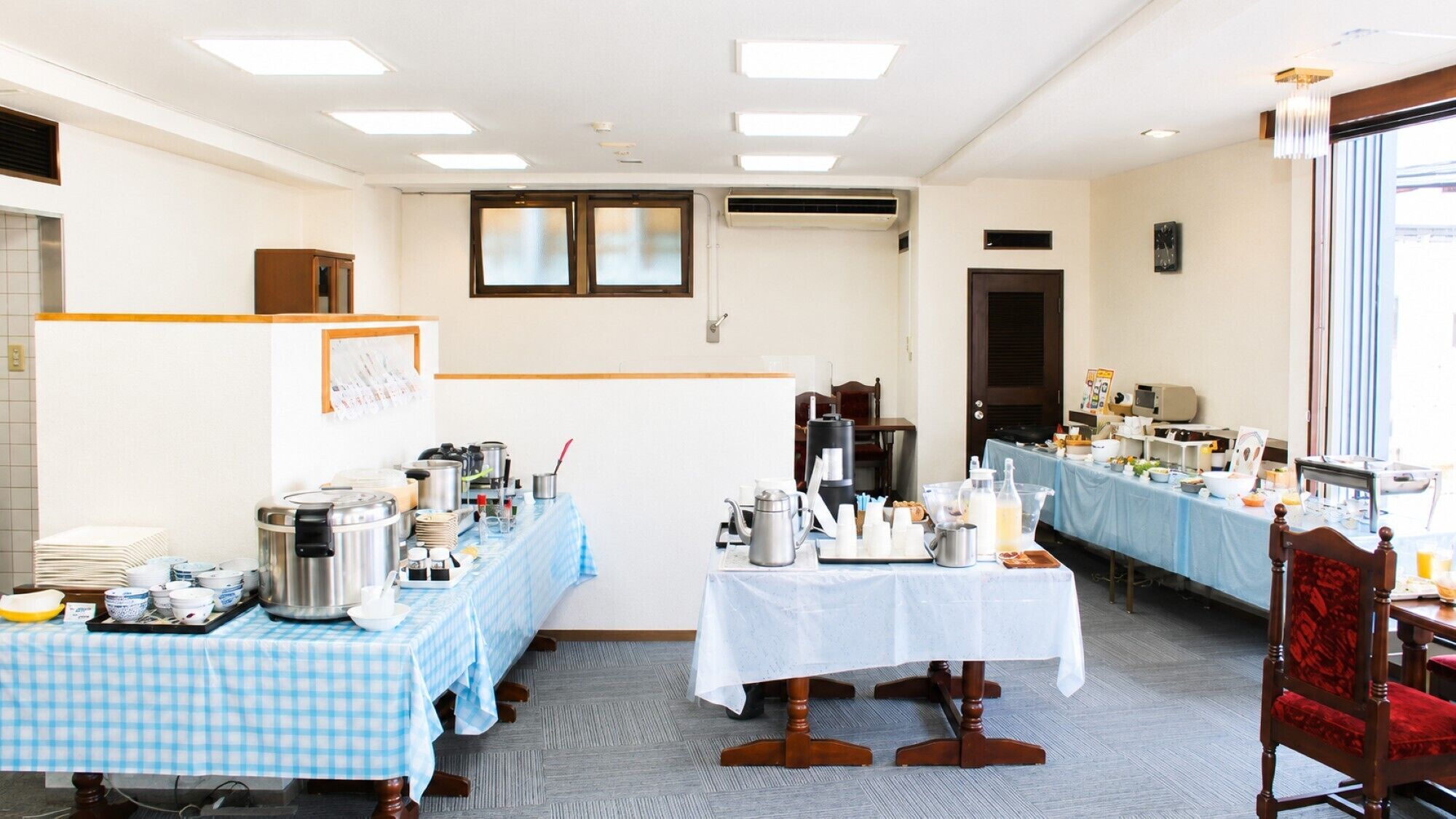 A hotel room with a checkered tablecloth, a coffee station, and a dining area with a blue tablecloth.